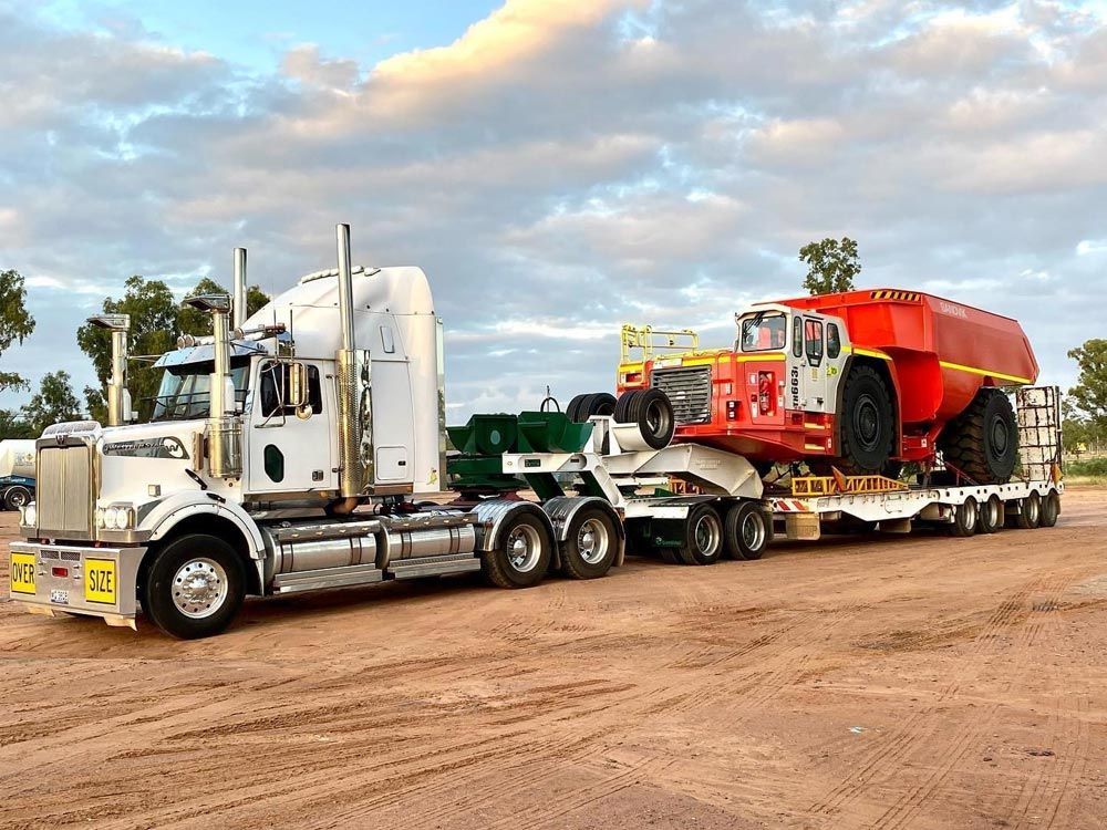 White Semi-truck Hauling A Large, Red And White Mining Vehicle — ECC Heavy Haulage in Ormeau, QLD