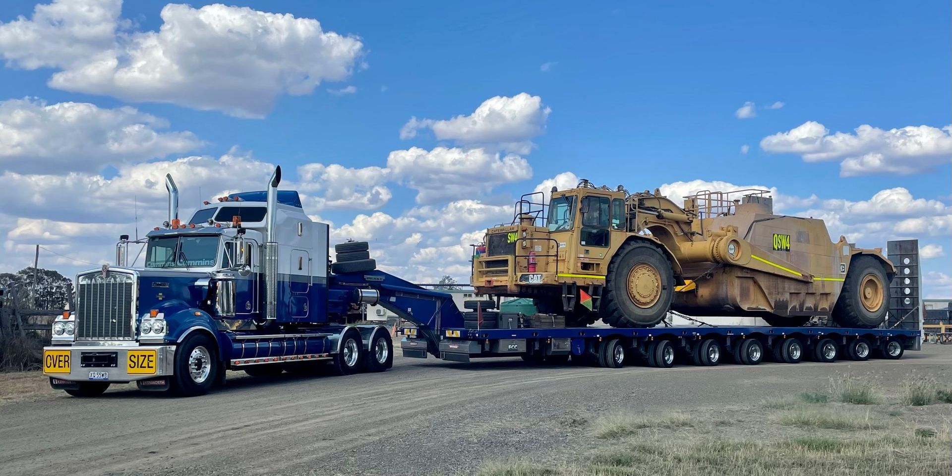 A Large Blue Semi-truck Hauling a Yellow Earthmover — ECC Heavy Haulage in Ormeau, QLD