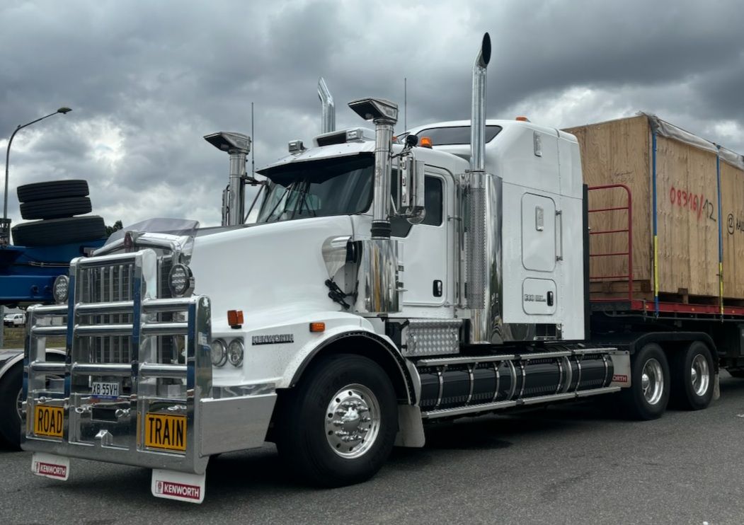 White semi-truck with chrome accents, hauling a large wooden crate on a flatbed trailer — ECC Heavy Haulage in Ormeau, QLD