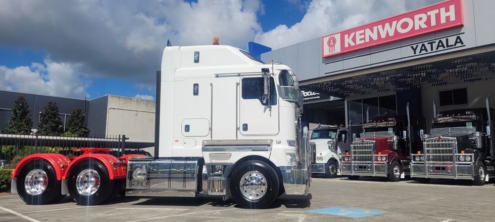 White Kenworth Truck Parked In Front Of A Kenworth Dealership — ECC Heavy Haulage in Ormeau, QLD