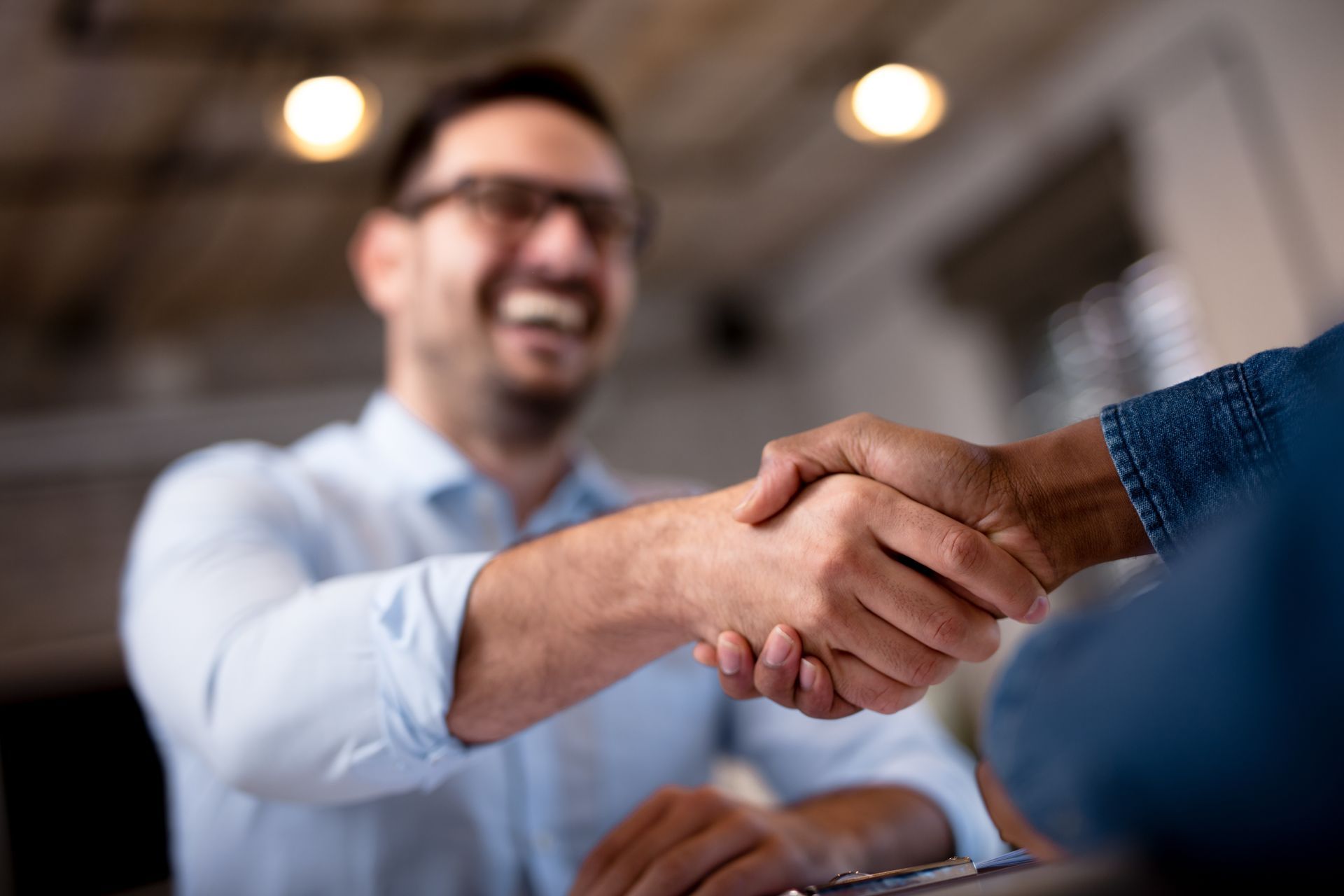Two people shaking hands, one smiling in an office setting.