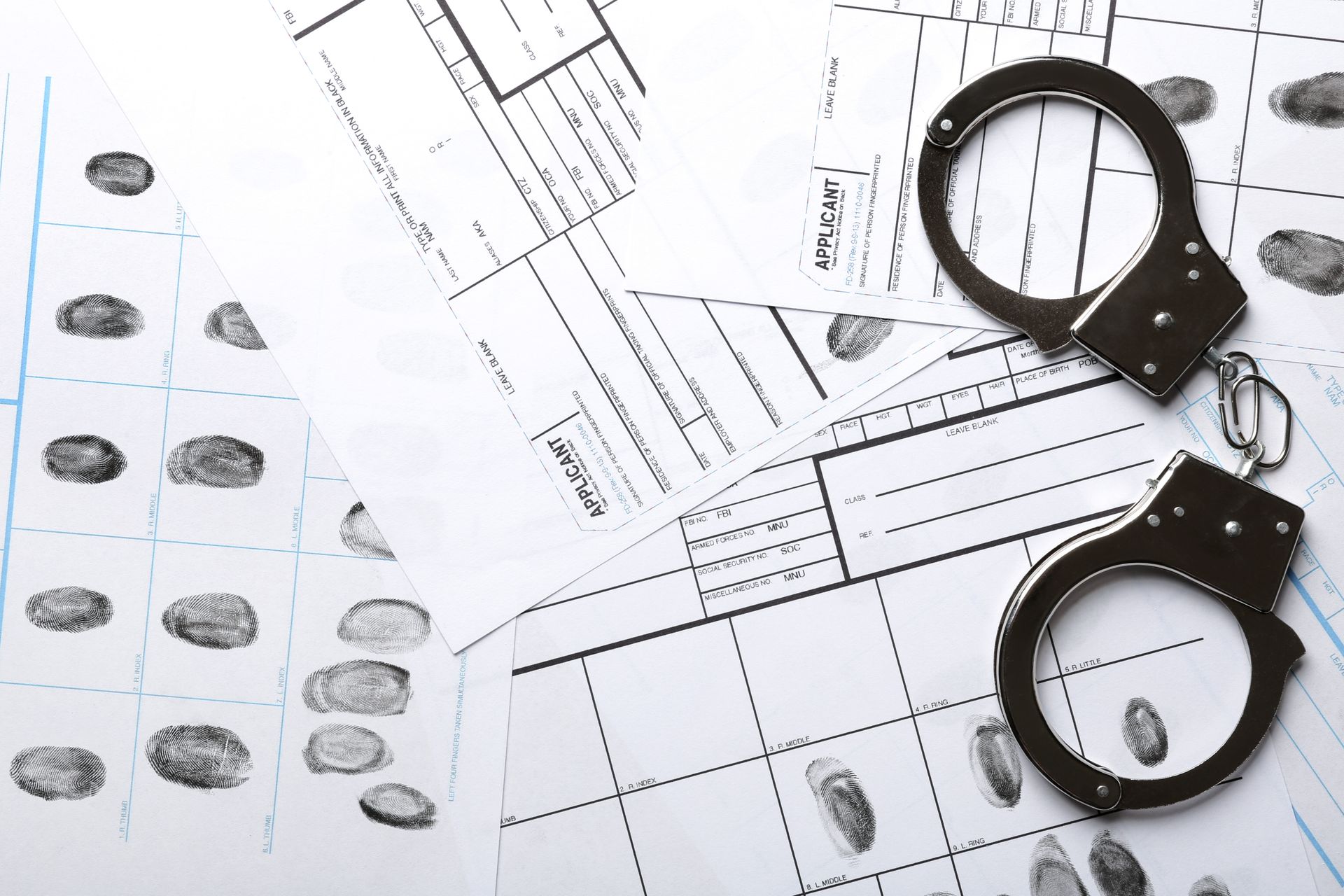Handcuffs resting on fingerprint analysis forms.