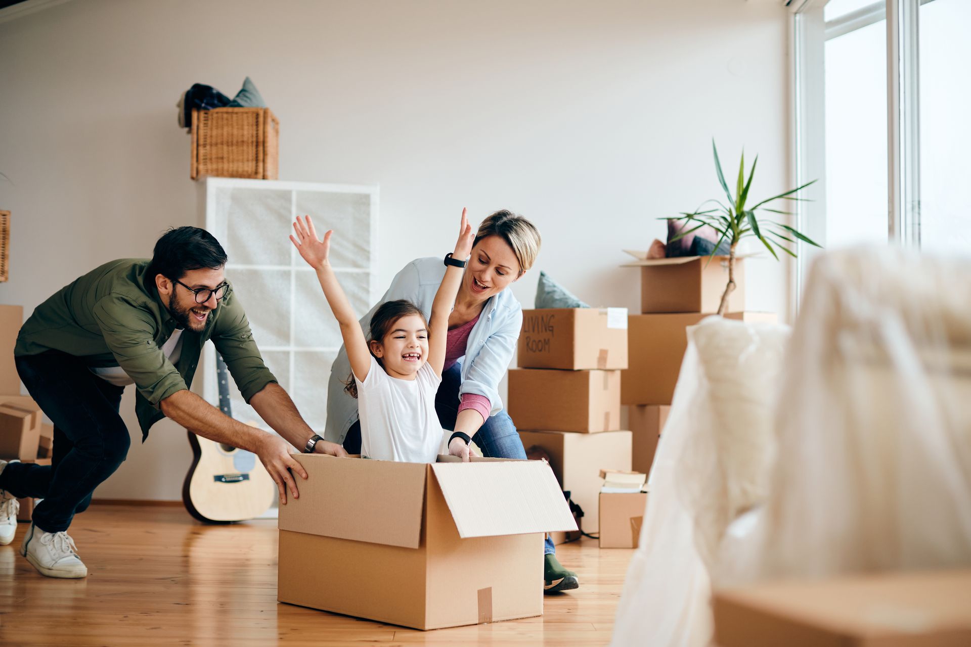 Family playing with cardboard box in new home.
