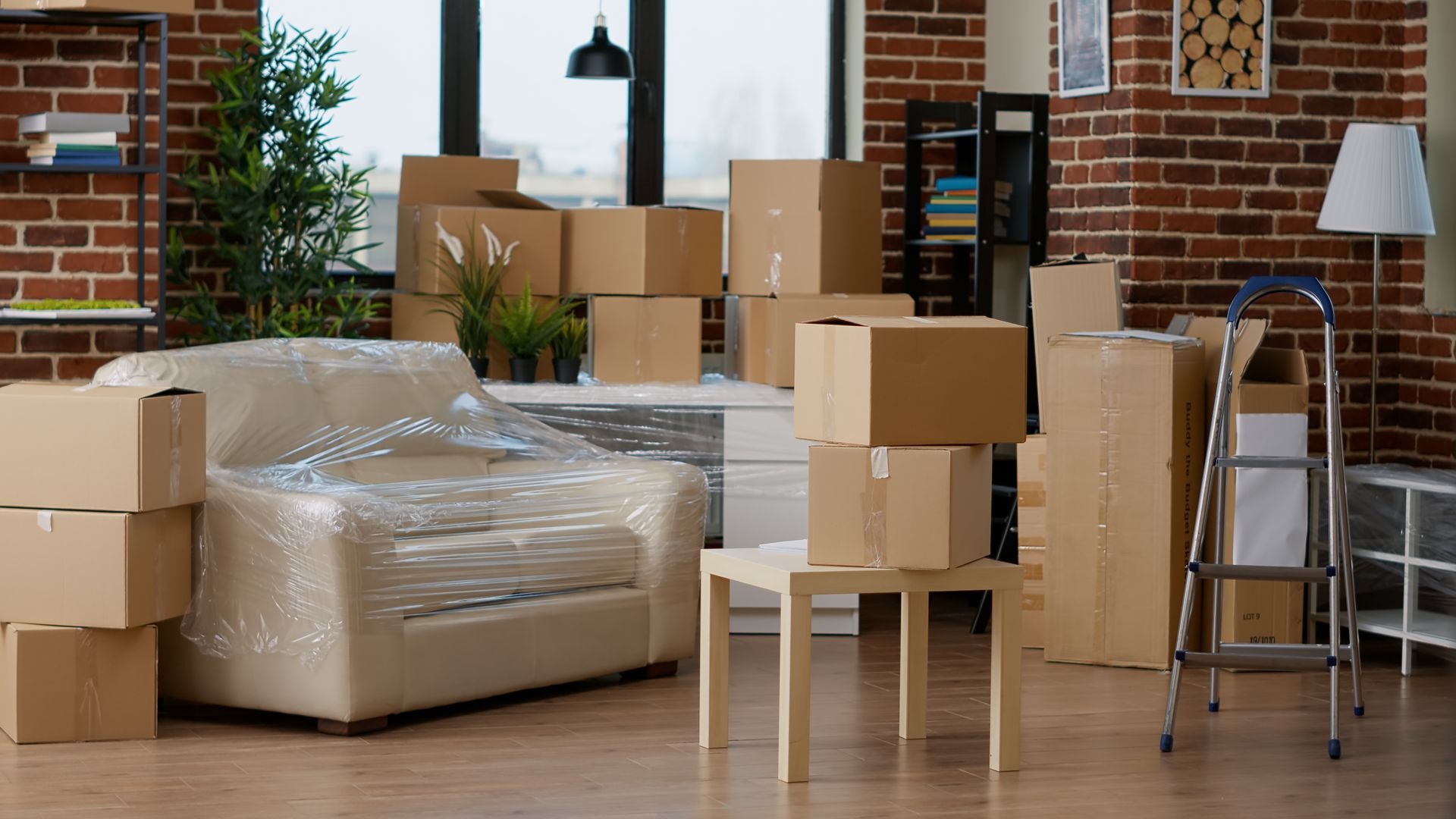 Movers loading boxes into a truck, next to a brick house. Sunny day.