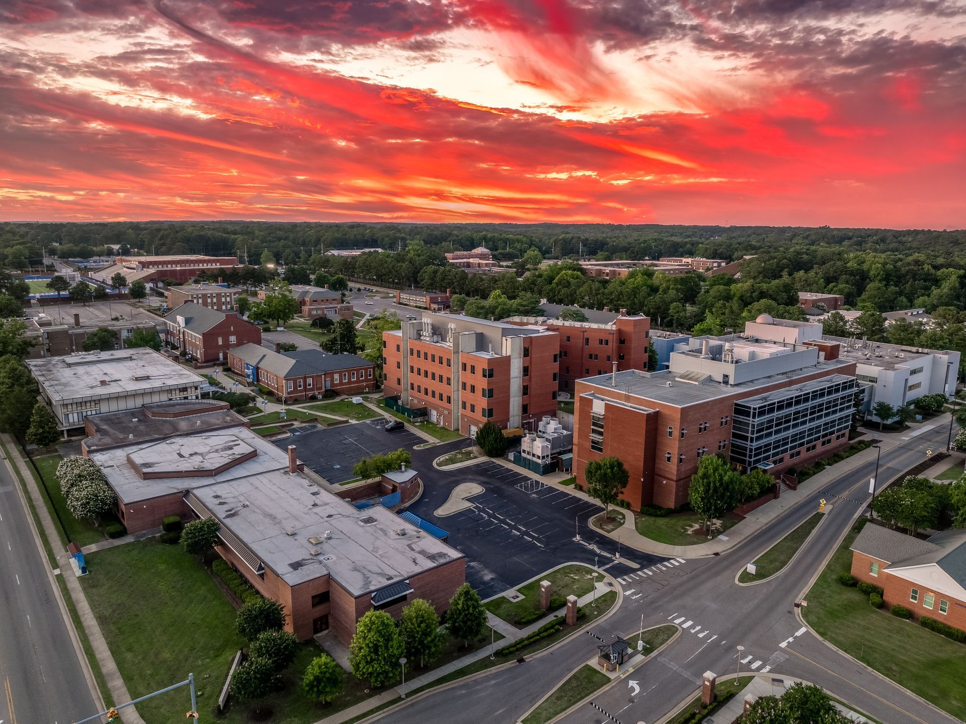 Aerial view of a hospital complex at sunset with fiery red and orange sky.