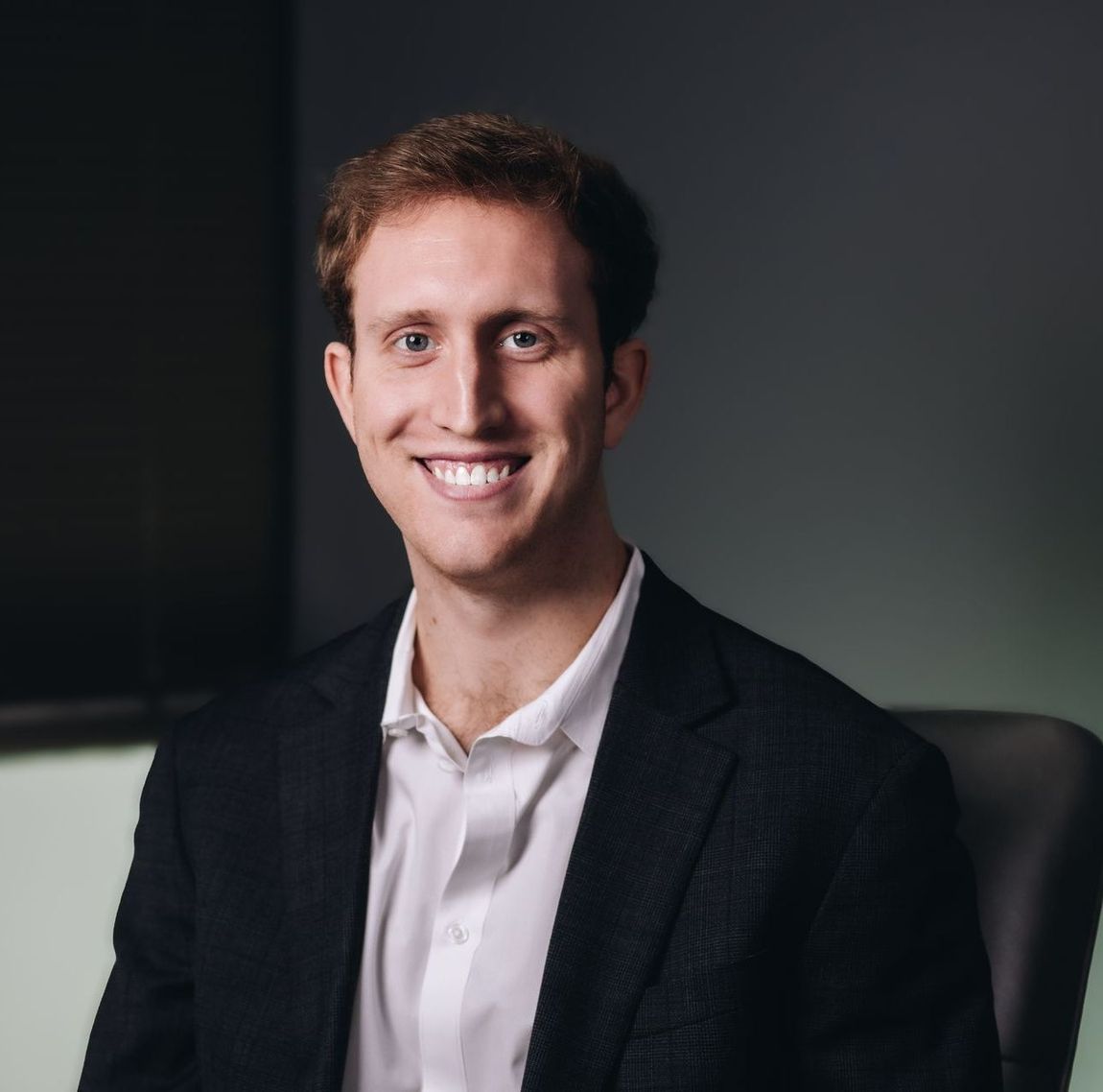 A man in a suit and white shirt is smiling for the camera