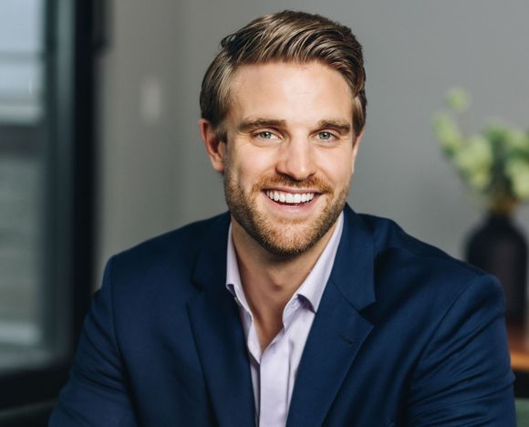  Elliott, a man smiling with a blue suit on. 