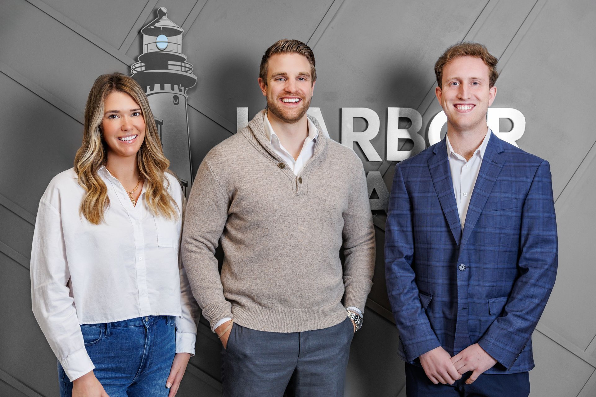 Three people standing in front of a gray wall with the word 