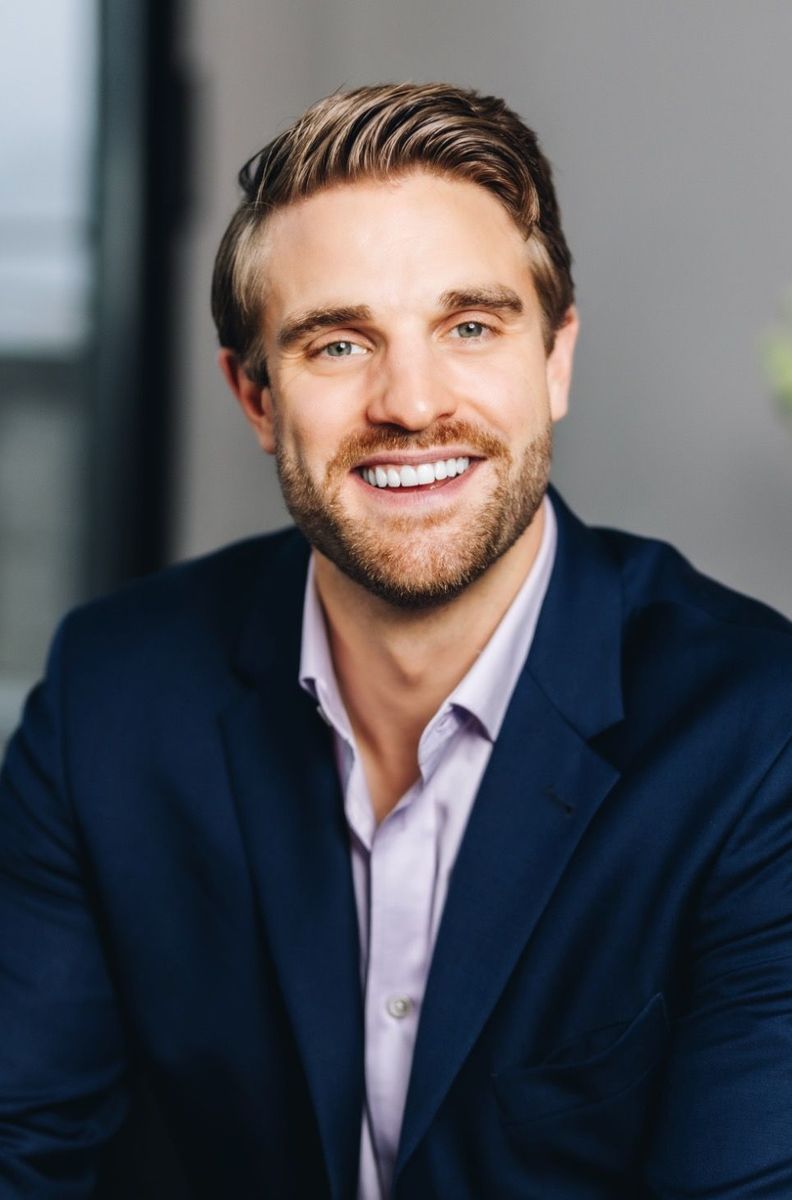A man in a suit and pink shirt is smiling for the camera.