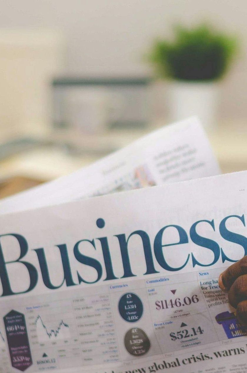 A person is reading a newspaper with the word business on it