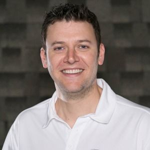 A man in a white polo shirt is smiling for the camera.