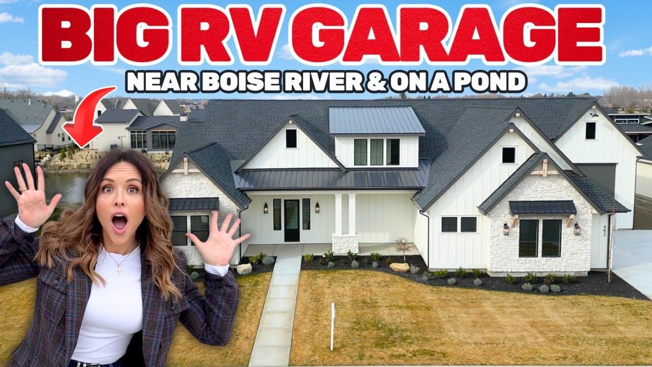 A woman stands with hands raised in surprise before a modern white house with a dark roof and large attached RV garage.