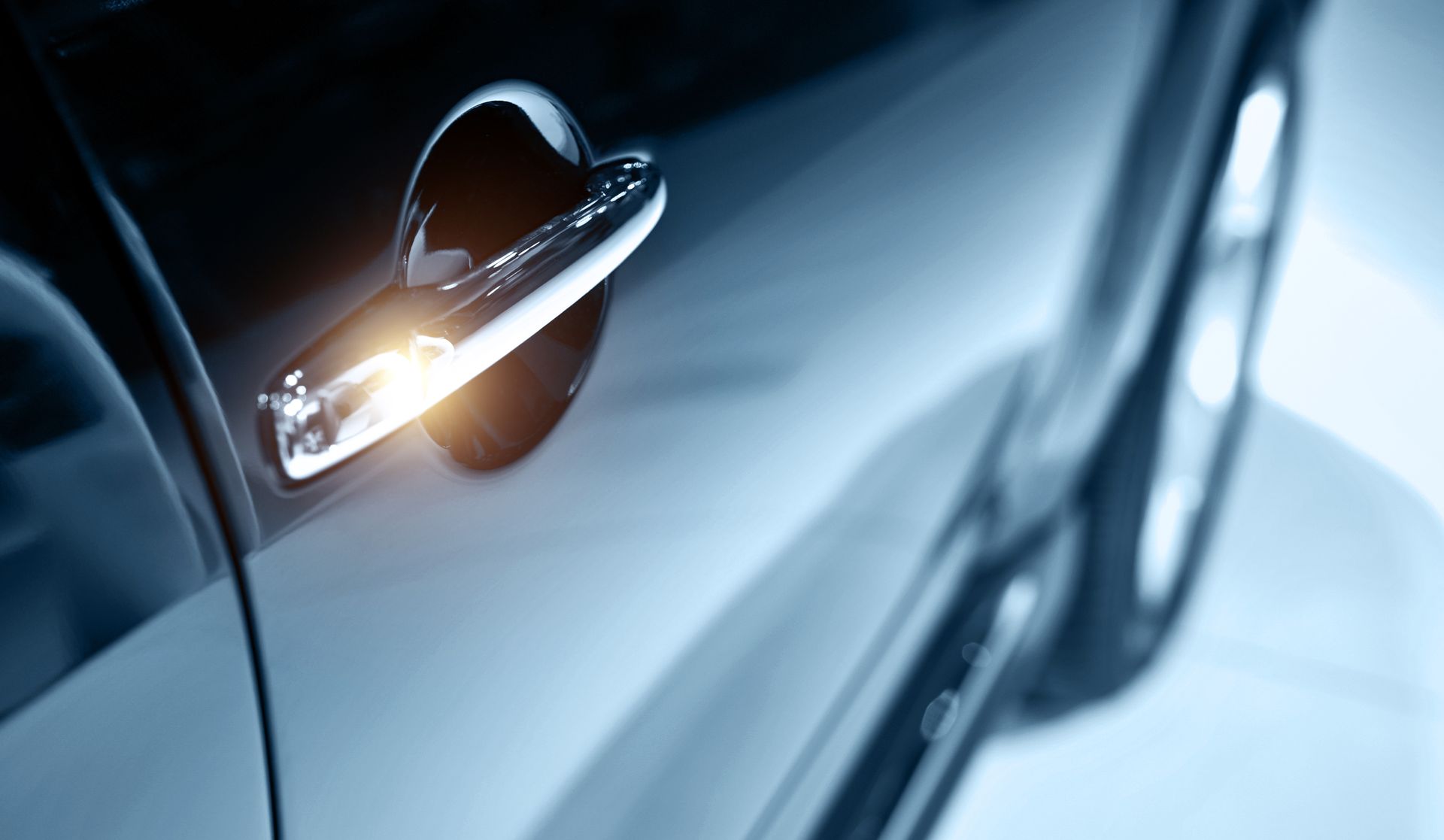 Shiny car door handle with an illuminated light.