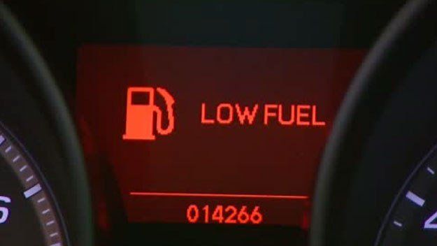 A low fuel sign is displayed on the dashboard of a car