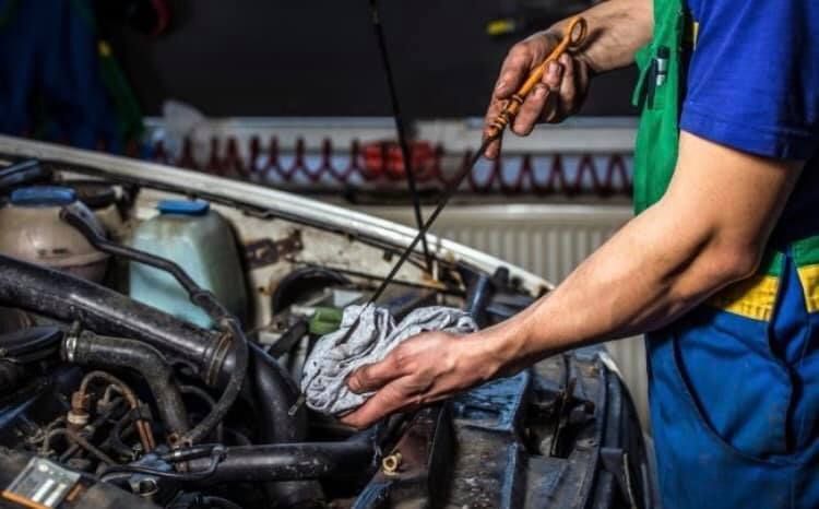 A man is checking the oil level of a car with a dipstick.