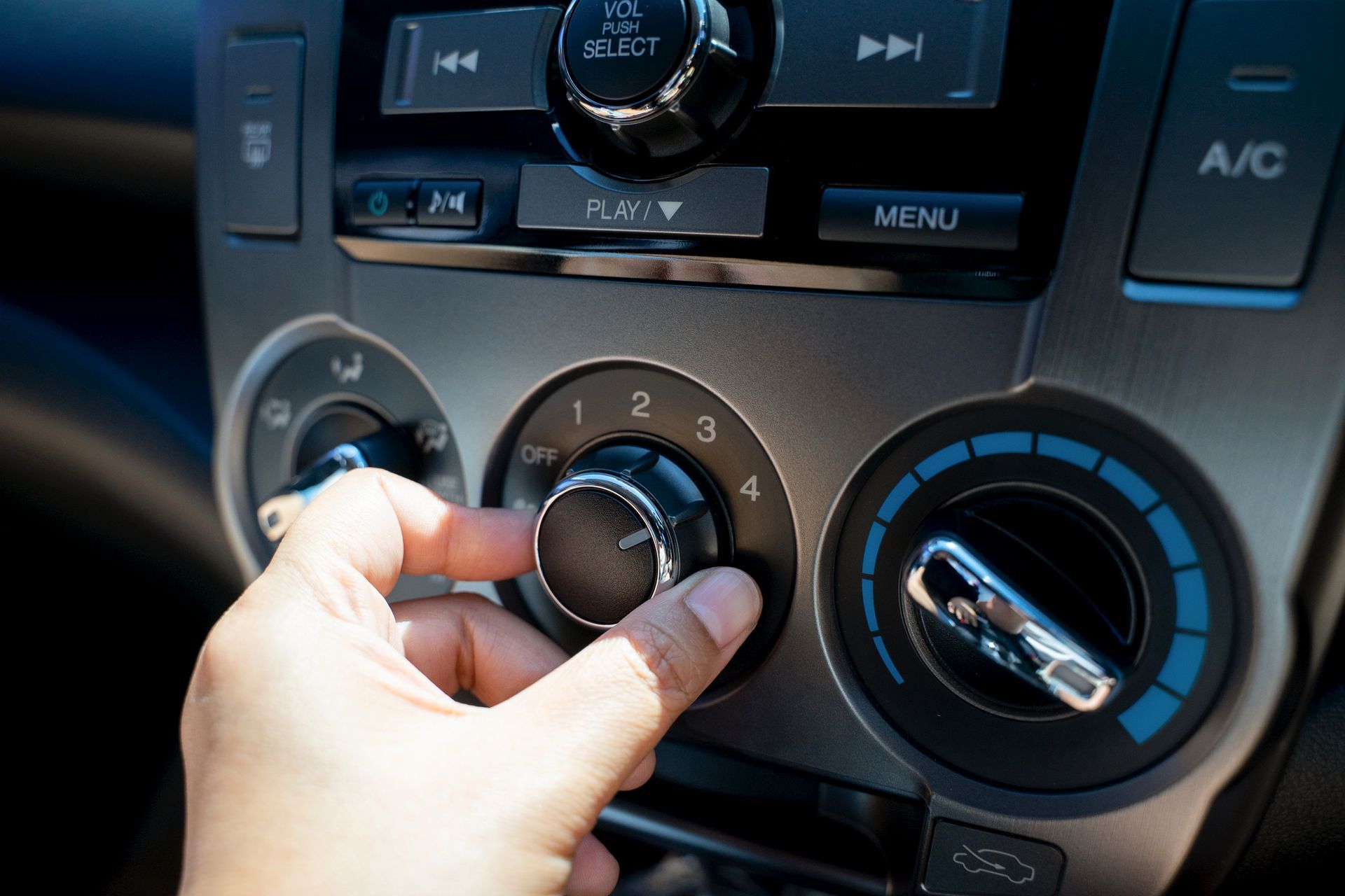 A person is adjusting the air conditioning in a car.