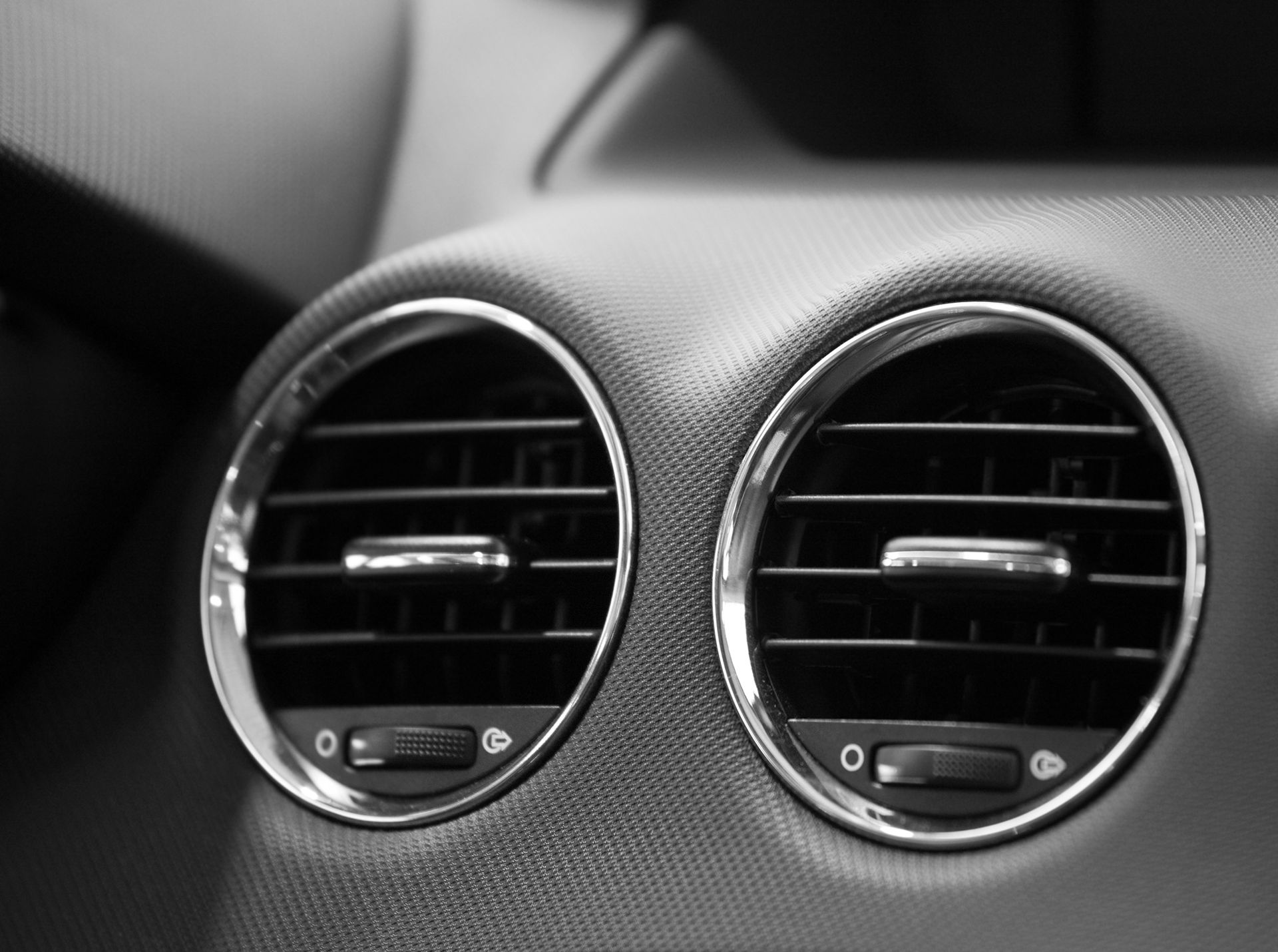A black and white photo of two air vents in a car