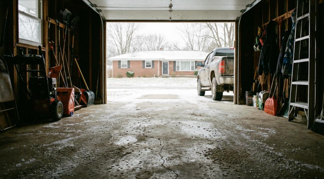 Open garage overlooking a snowy driveway, with a truck parked outside.