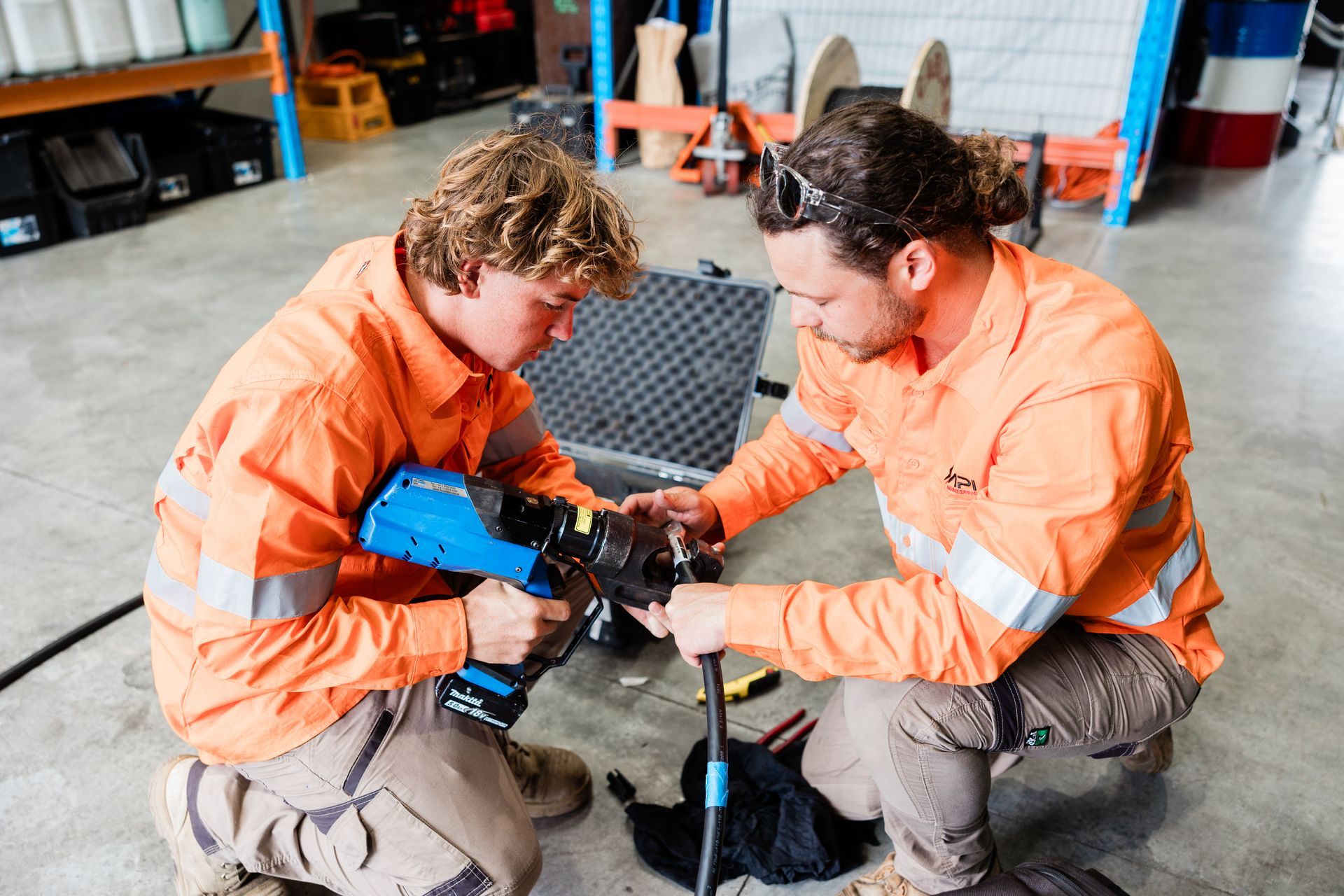 Two Workers Focus Intently on Using a Tool for Cable Work — API Engineering in Charmhaven, NSW