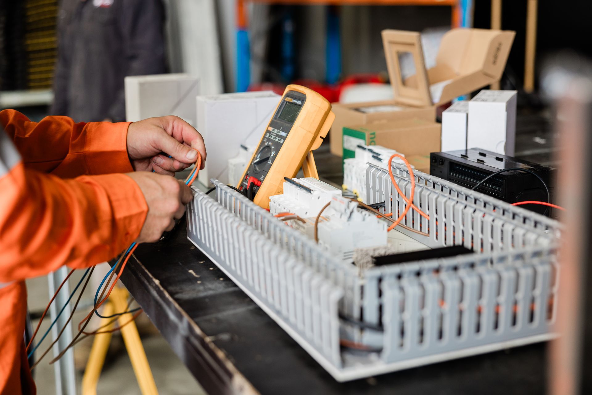 A Person Works With Wires and Electrical Equipment on a Table — API Engineering in Charmhaven, NSW