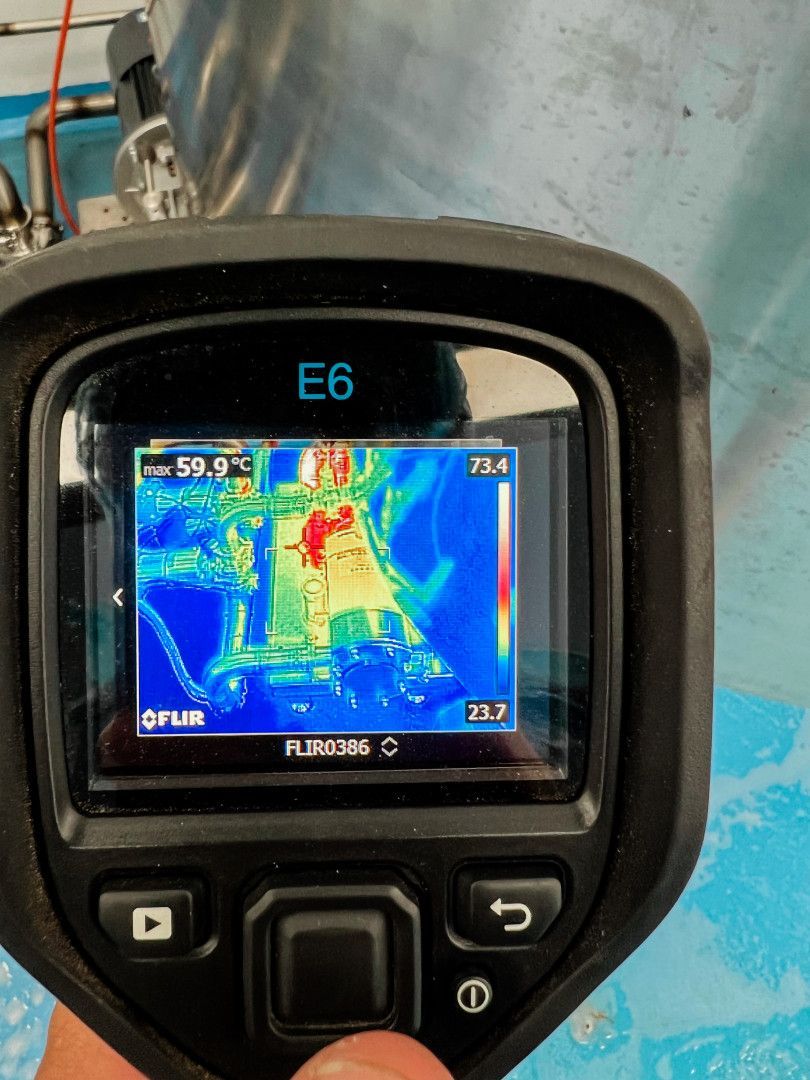 Thermal camera showing a red-hot mechanical component against a blue backdrop, indicating heat.