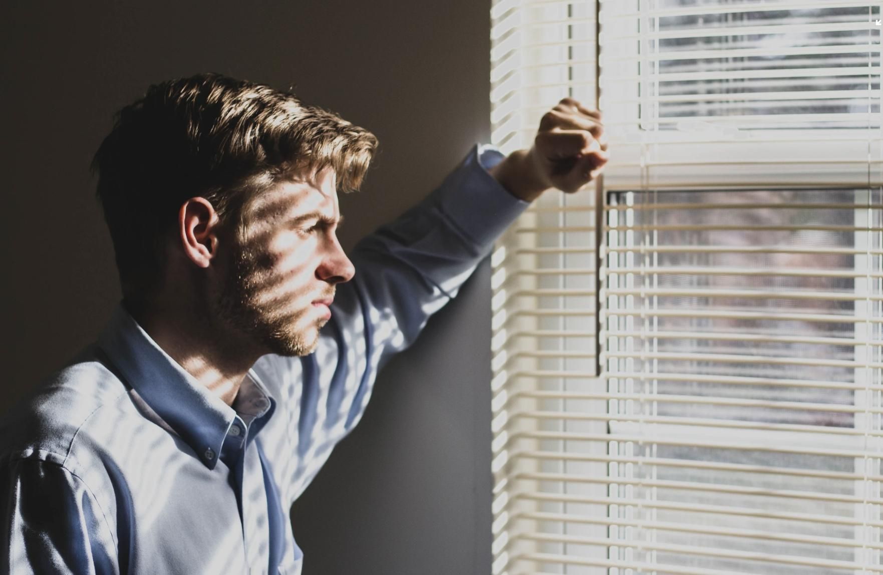 A Man is Looking Out of a Window With Blinds — Wow Clean Cairns in Bayview Heights, QLD
