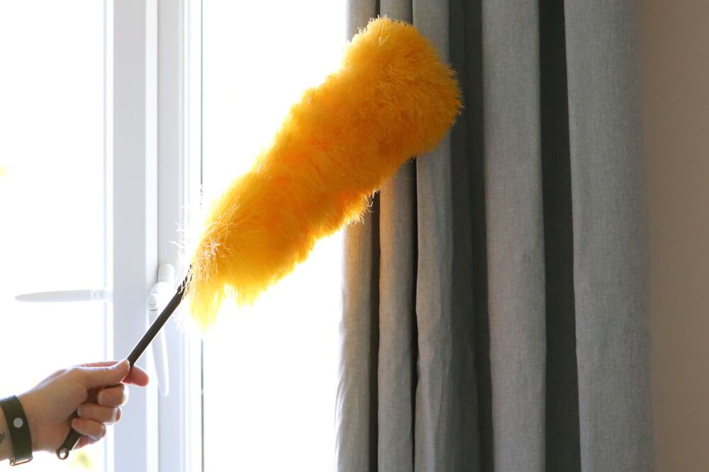 Lady cleaning around window and curtain pole — Curtain & Blind Cleaners in Bayview Heights, QLD
