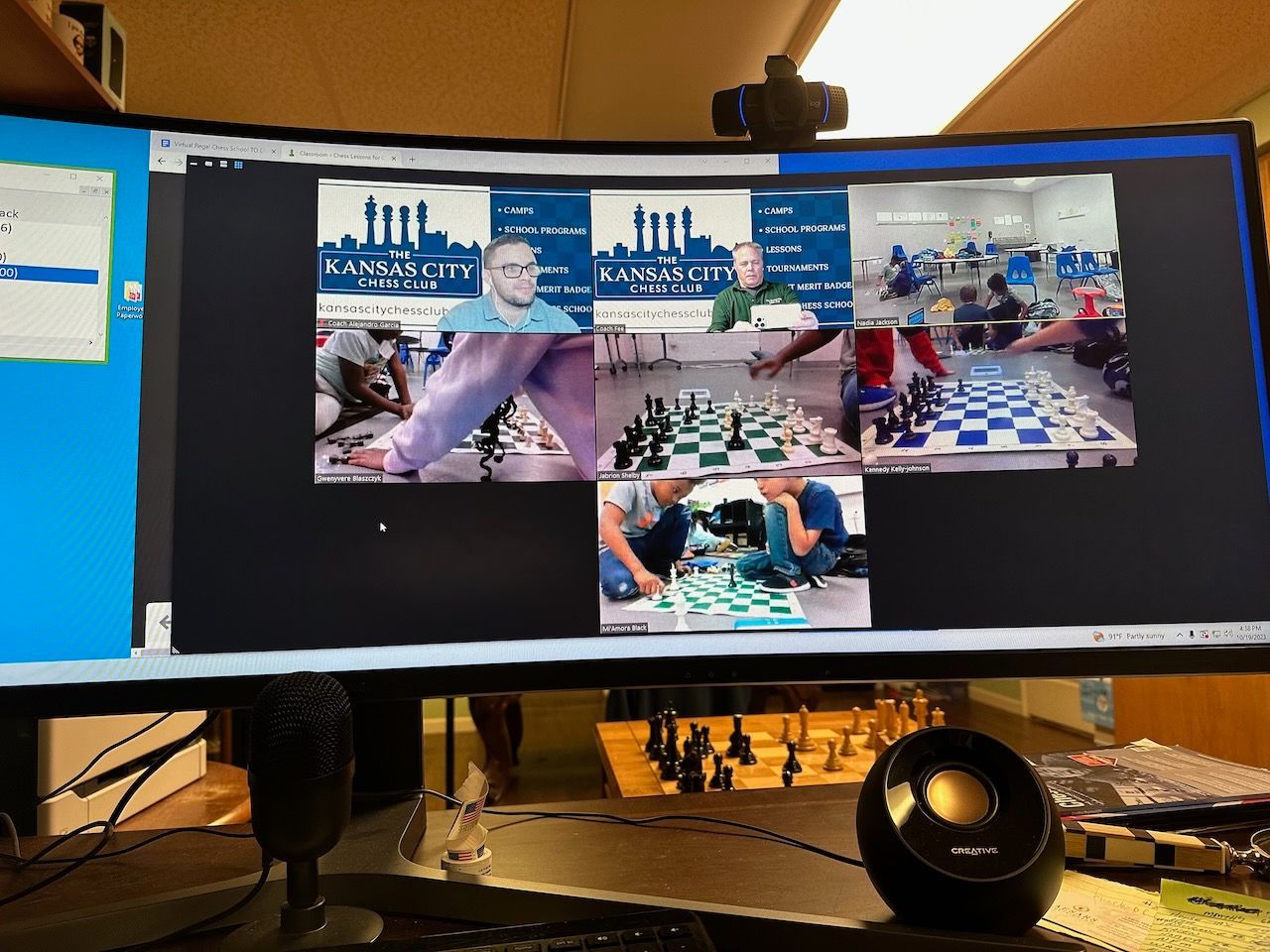 A computer monitor shows a group of people playing chess