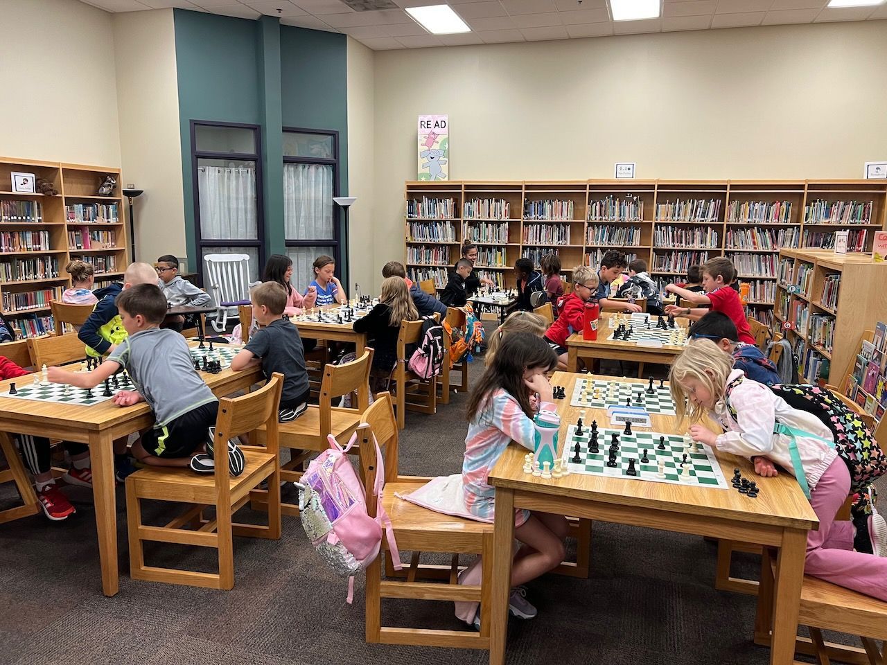 A group of children are playing chess in a library.