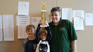 A woman and two children are holding a trophy in a room.