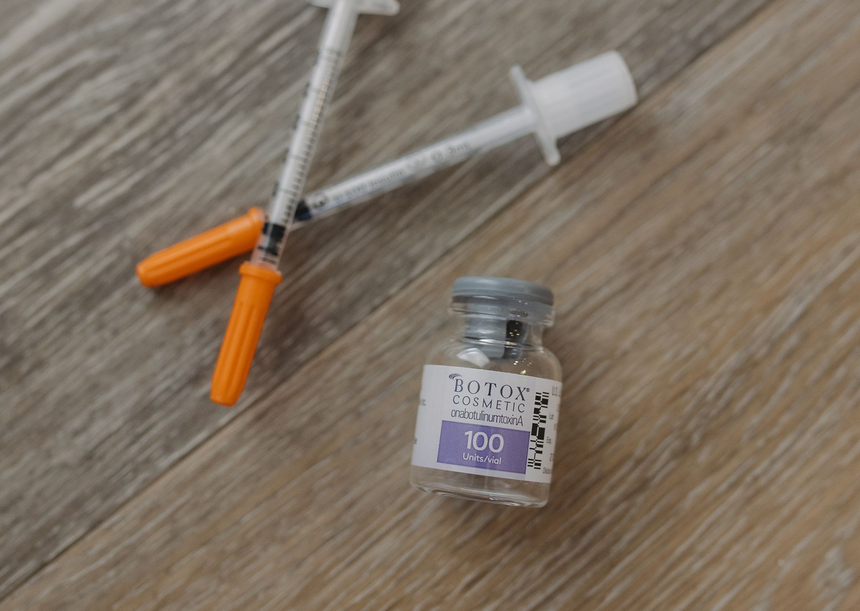 Syringe with orange caps beside a small glass medicine vial on a wooden surface