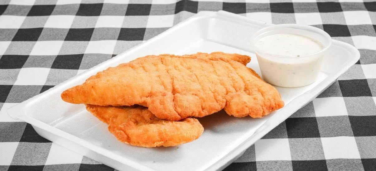 Fried chicken tenders with ranch dipping sauce, with a black and white checkered tablecloth.