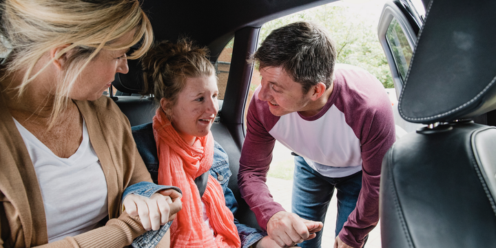 A man and two women are sitting in the back seat of a car.