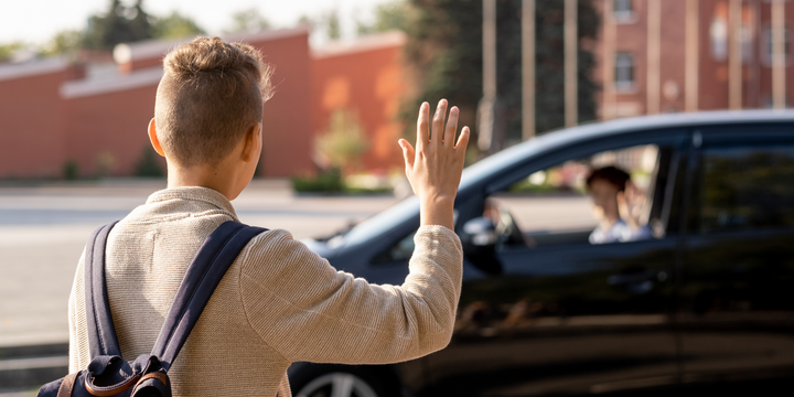 A man with a backpack is waving at a car.