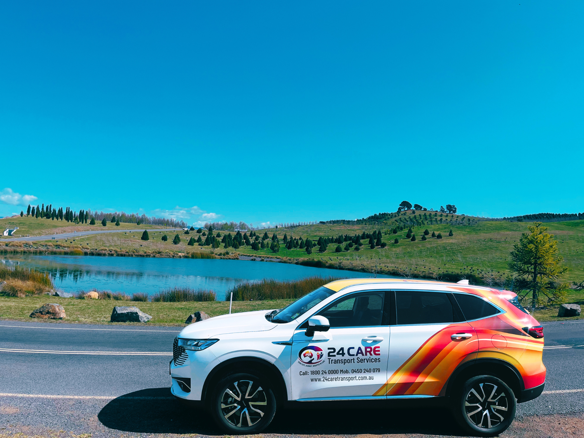 A car is parked on the side of the road next to a lake.