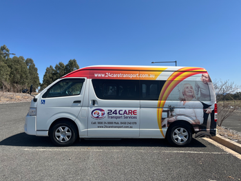 A white van with a picture of an elderly woman on the side is parked in a parking lot.