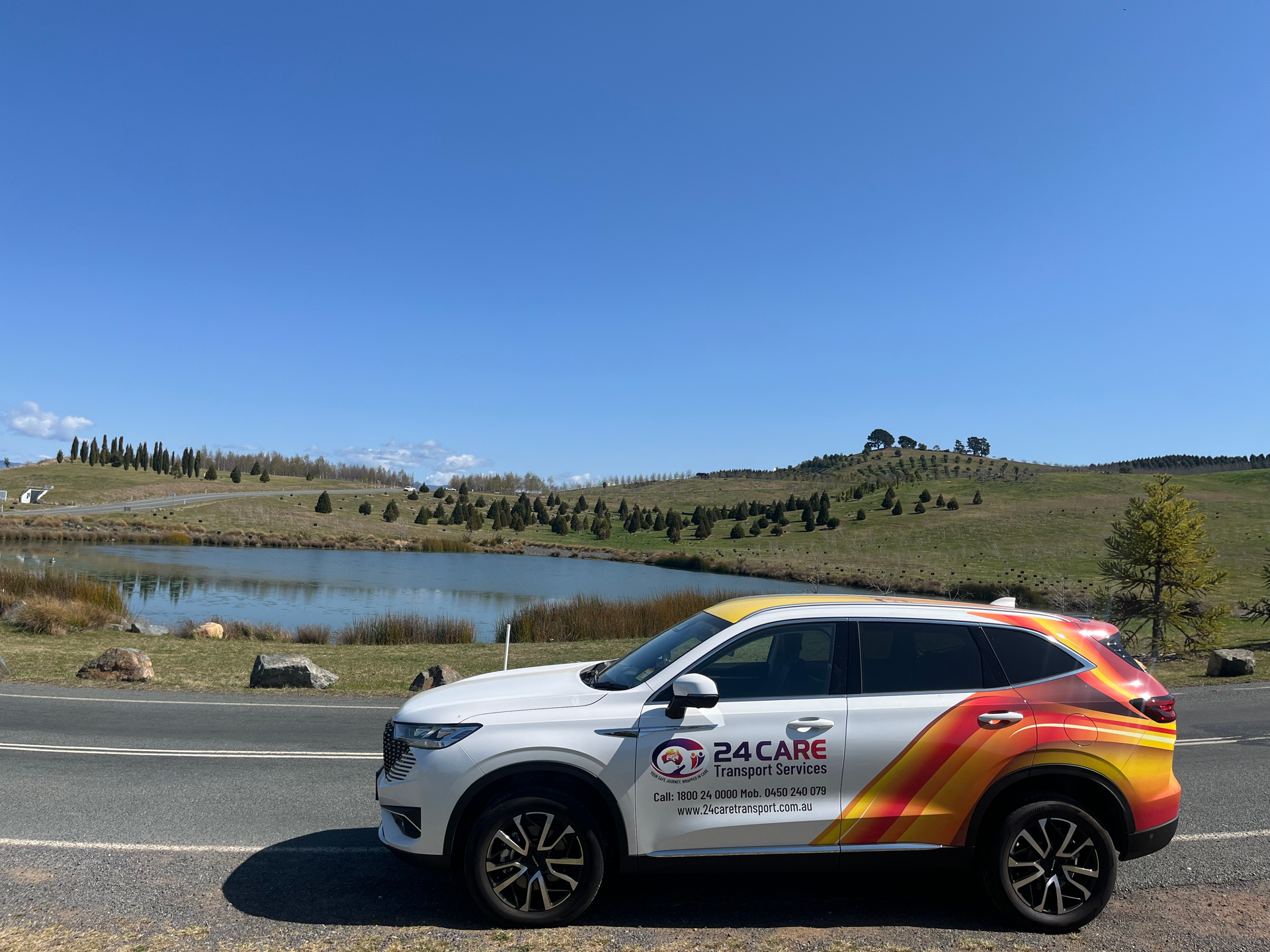 A car is parked on the side of the road next to a lake.