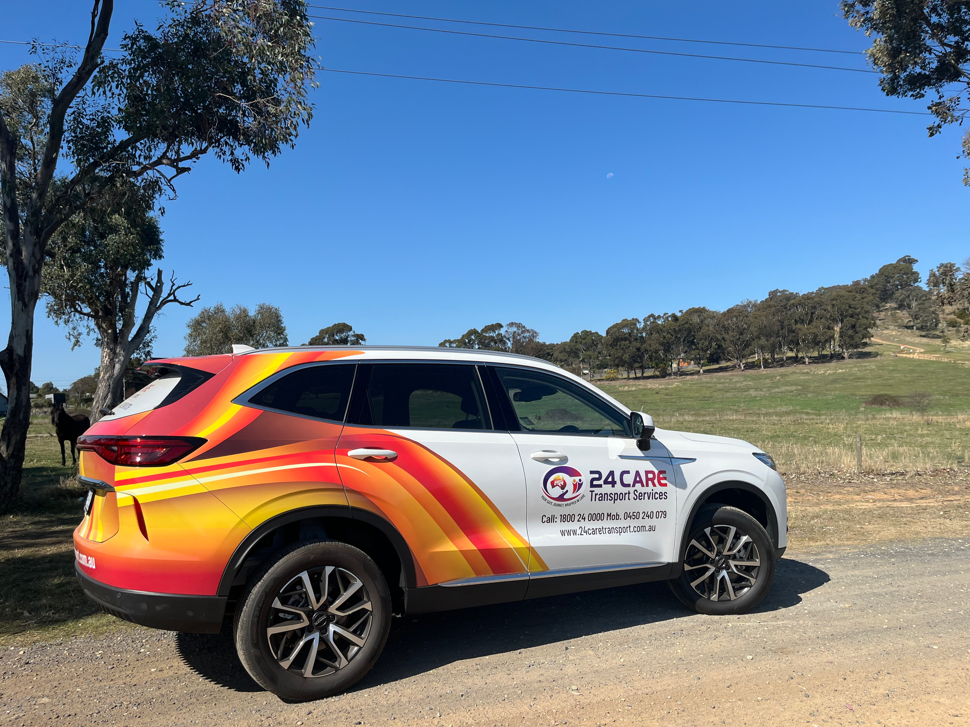 A colorful car is parked on the side of a dirt road.