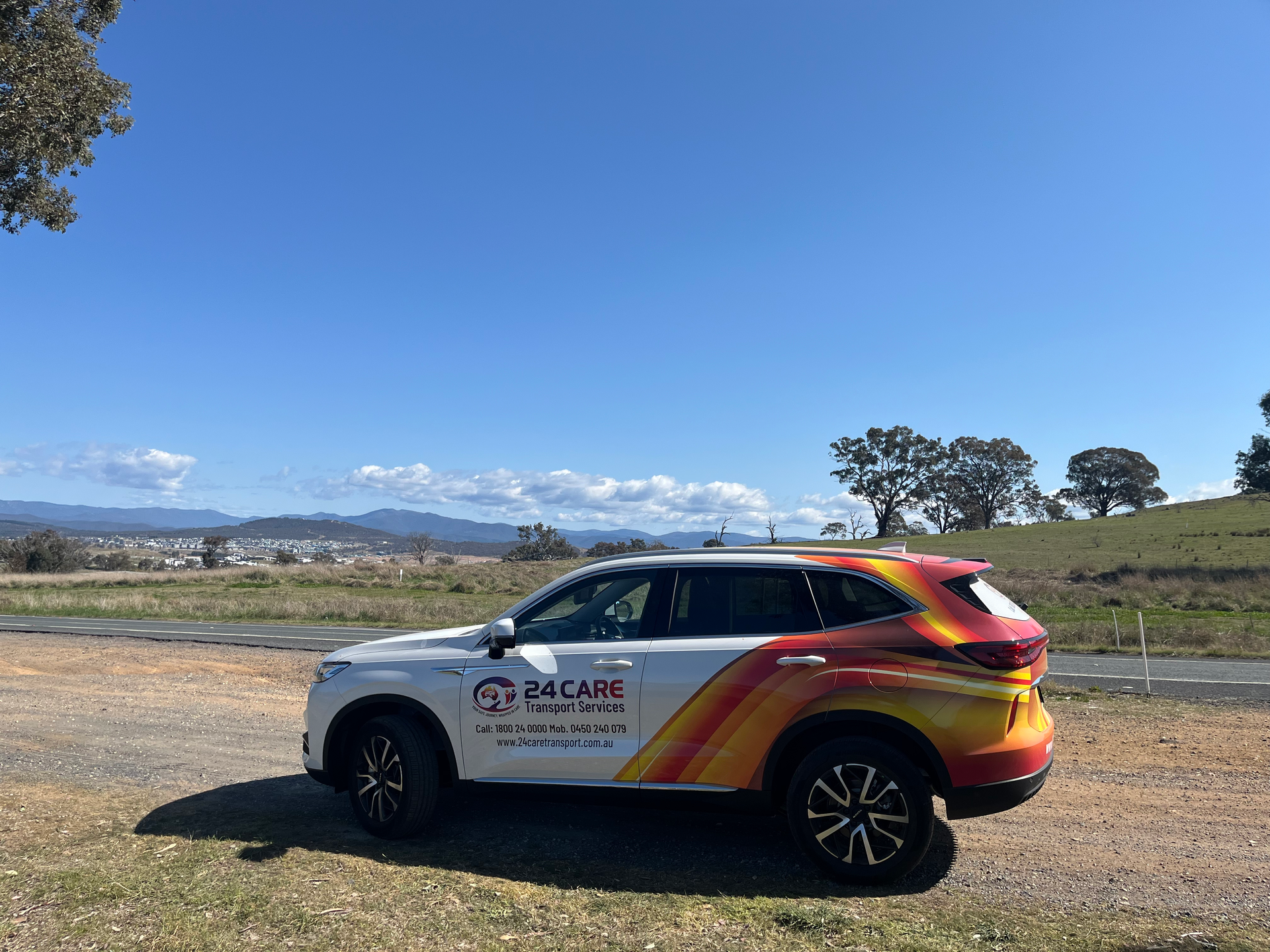 A car is parked on the side of the road in a field.