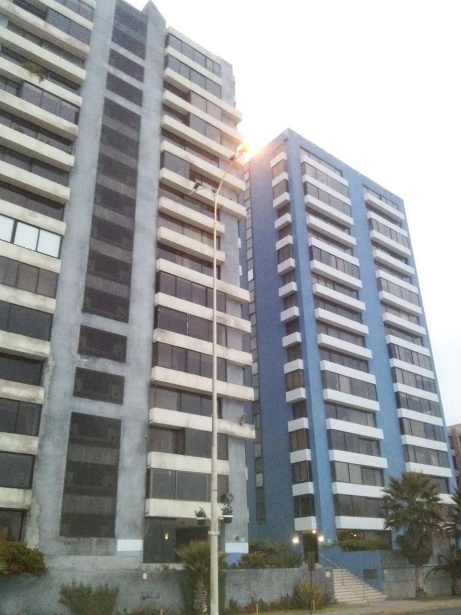 Dos altos edificios de apartamentos de color azul y gris se encuentran uno al lado del otro, en un día nublado.