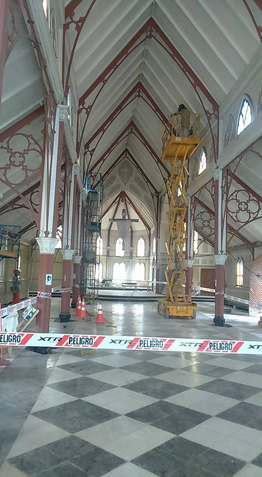 Vista interior de una gran iglesia destripada en proceso de renovación. Suelo de tablero de ajedrez, andamios y ascensor.
