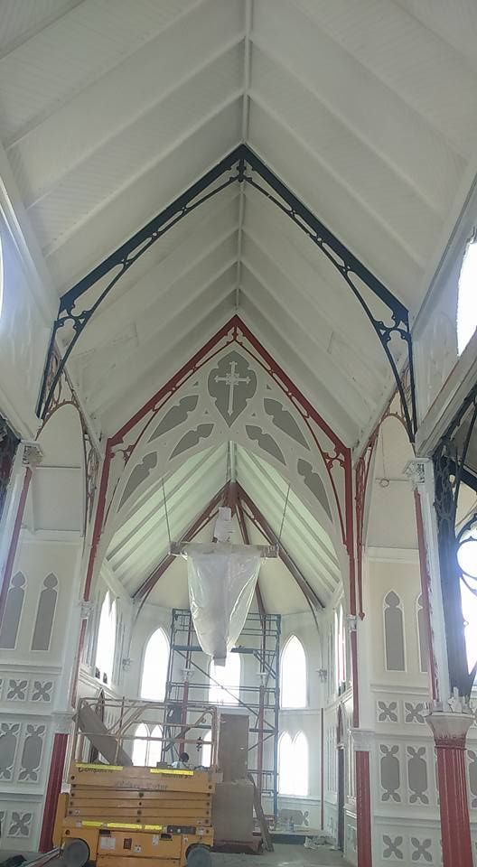 Interior de una iglesia con techo abovedado blanco, molduras intrincadas y grandes ventanales.