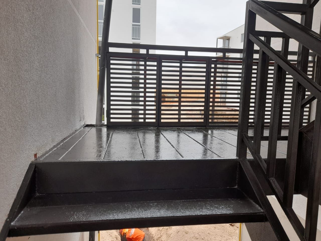 Tres personas en una mesa revisando muestras de diseño, el hombre centrado, las mujeres flanqueándolo, fondo de panel de madera.