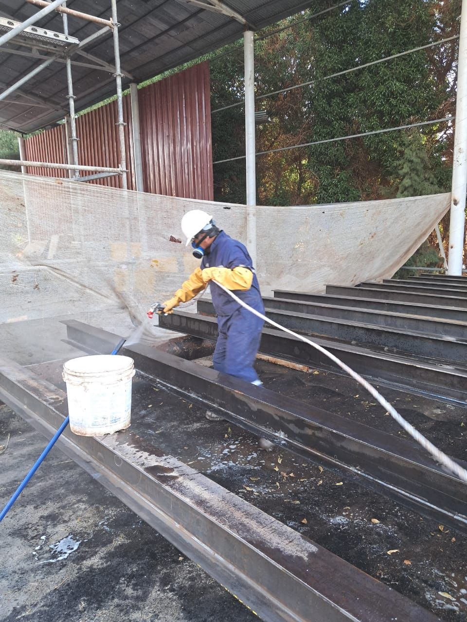 Persona con equipo de protección pulverizando rayos en un sitio de construcción.