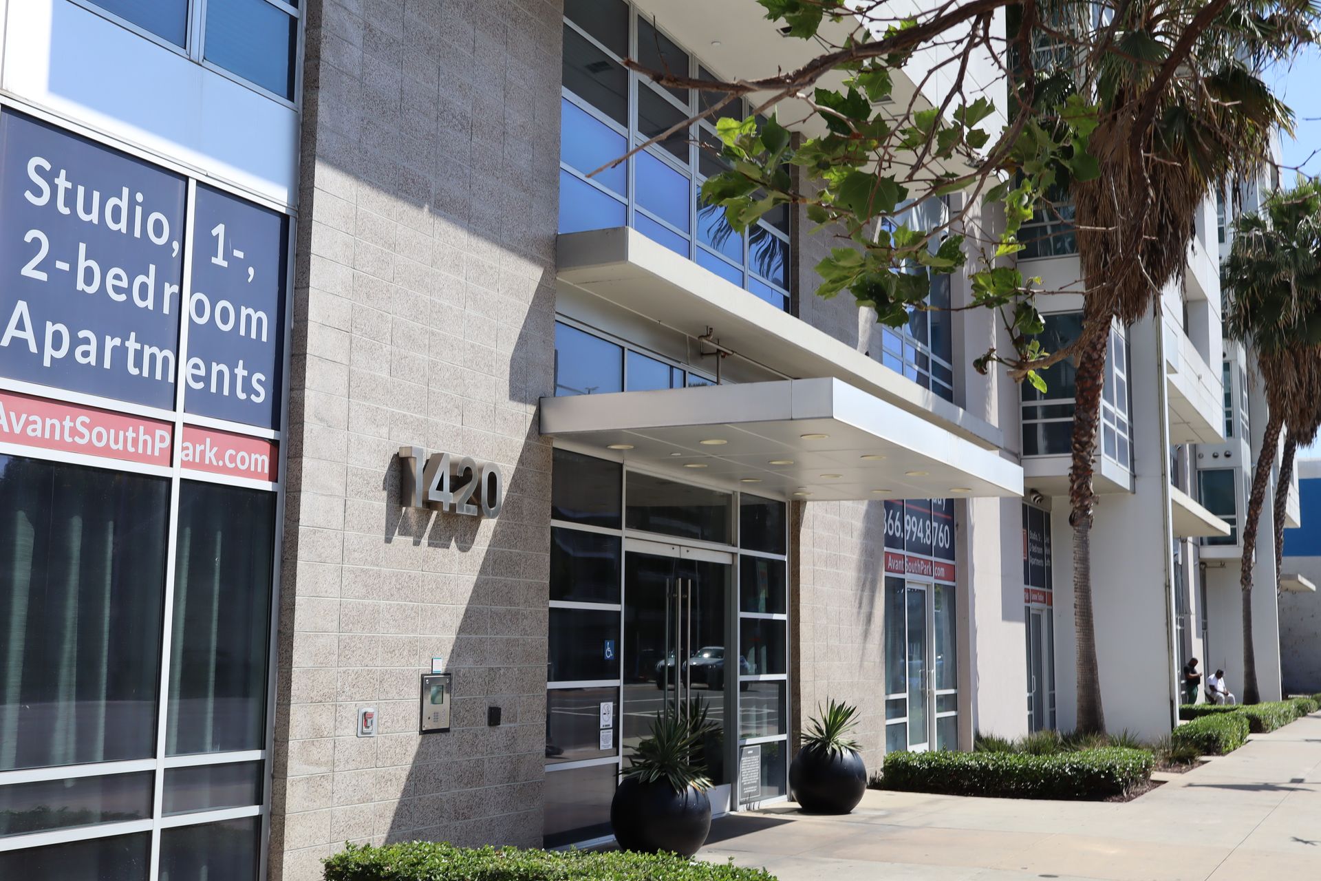 Apartment building entrance with glass doors, awnings, and a sign for studio and 2-bedroom apartments