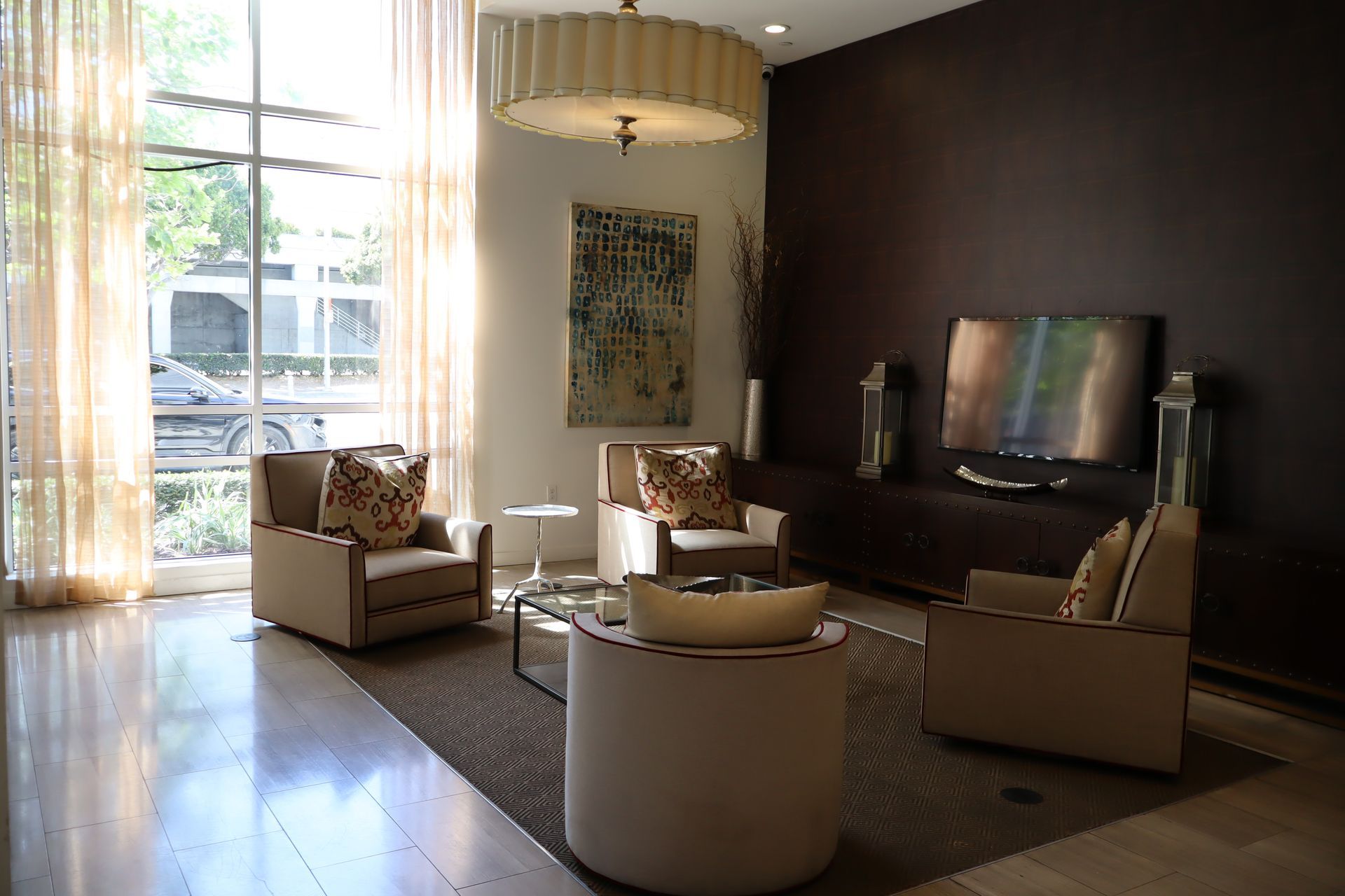 Modern living room with beige chairs, dark accent wall, large window, and TV on the right