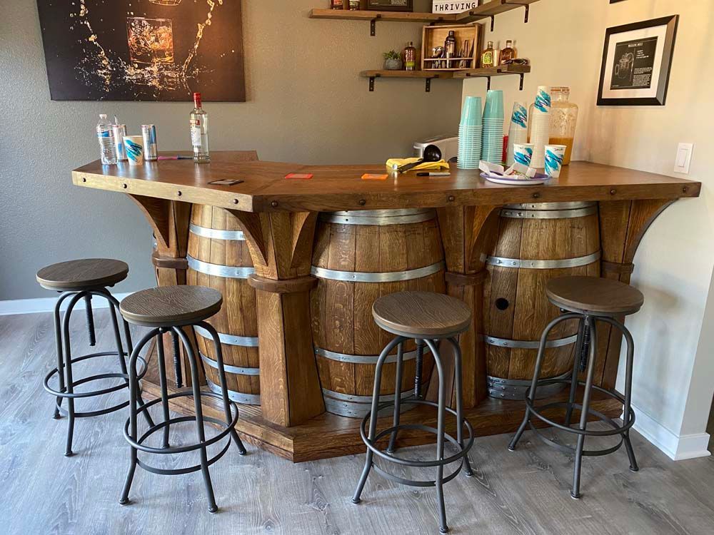 A wooden bar with barrels and stools in a room.