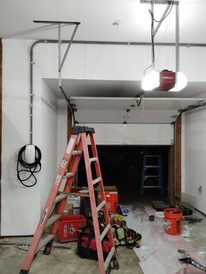 Garage under construction with red ladders, tools, and hanging lights