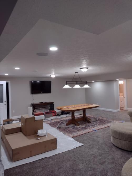 Living room with a pool table, TV, sectional sofa, and moving boxes under recessed lighting