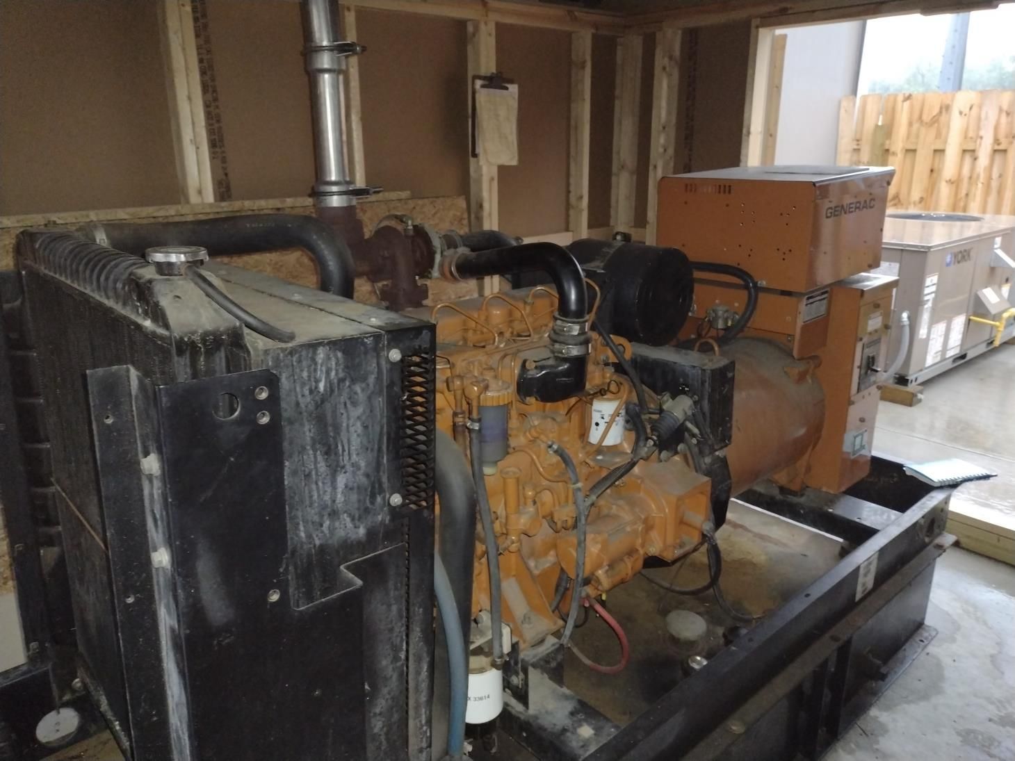 Industrial generator set with orange engine and black radiator in a utility room
